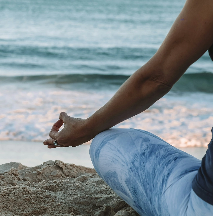 Persoon doet een mindfulness-meditatie op het strand met uitzicht op de zee.