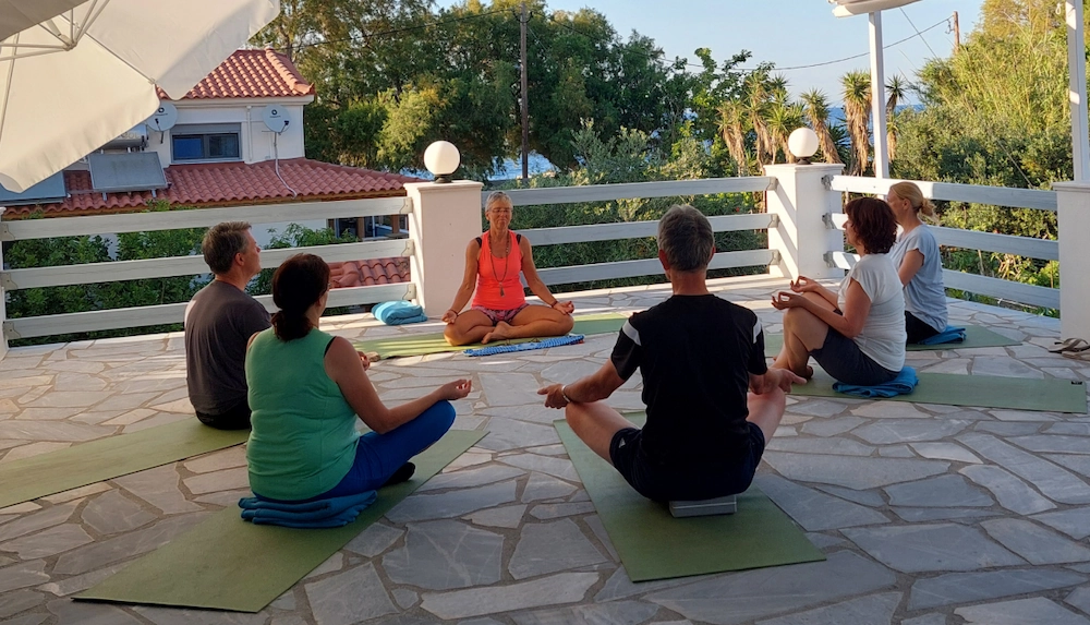 Groep mensen doet een meditatiesessie op een zonnig terras tijdens het Marjaani Private Retreat.