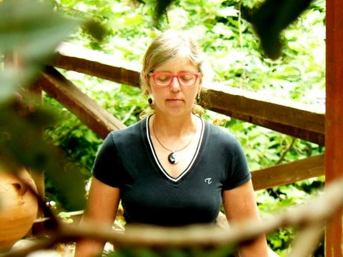 Vrouw doet Qi Gong-oefening in een groene, bosrijke omgeving.