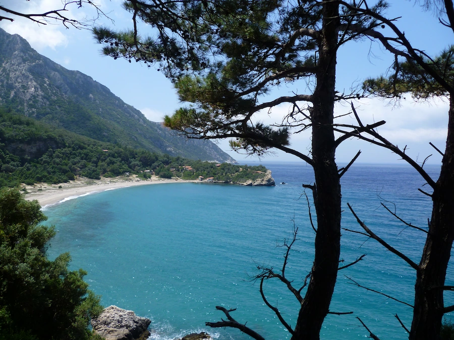 Uitzicht op het afgelegen Marjaani-strand op Samos met turquoise zee, omringd door bergen en pijnbomen.
