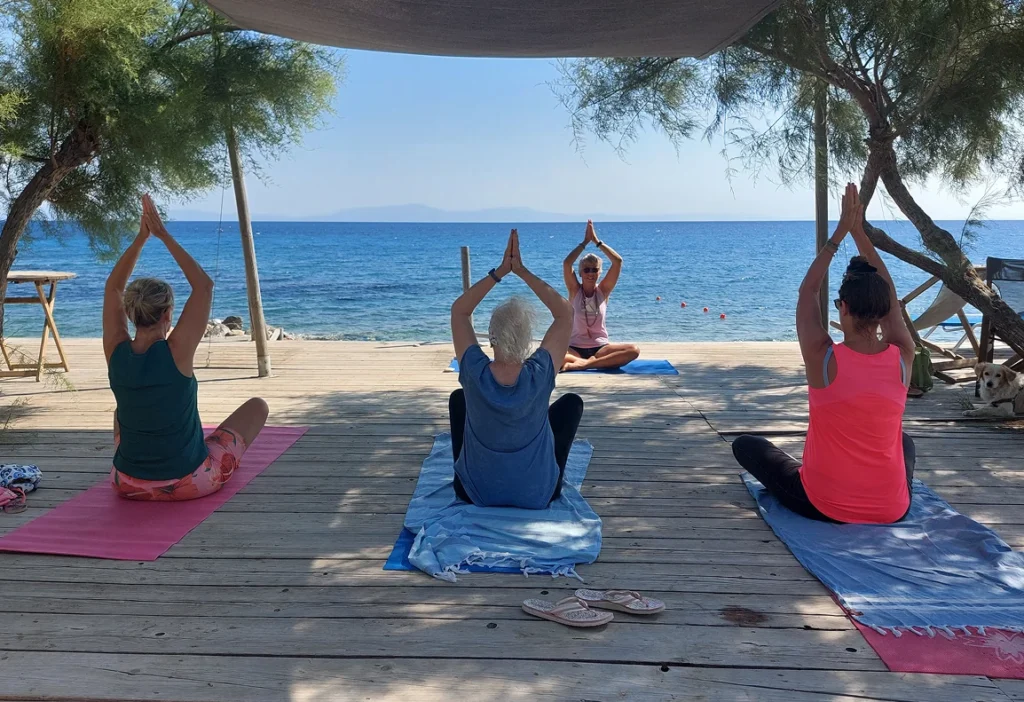 Vrouwen doen yogaoefeningen op een houten vlonder aan zee bij Marjaani Samos.