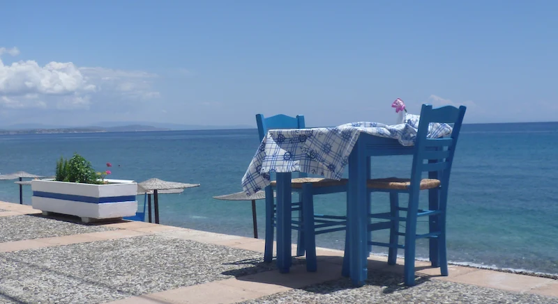 Blauw Marjaani-tafeltje met stoelen aan zee met uitzicht op de horizon.