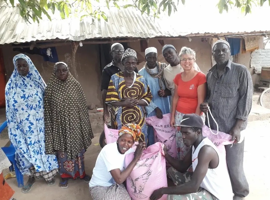 Een groep mensen poseert samen met grote voedselzakken in het dorp met Marjaani in Gambia.